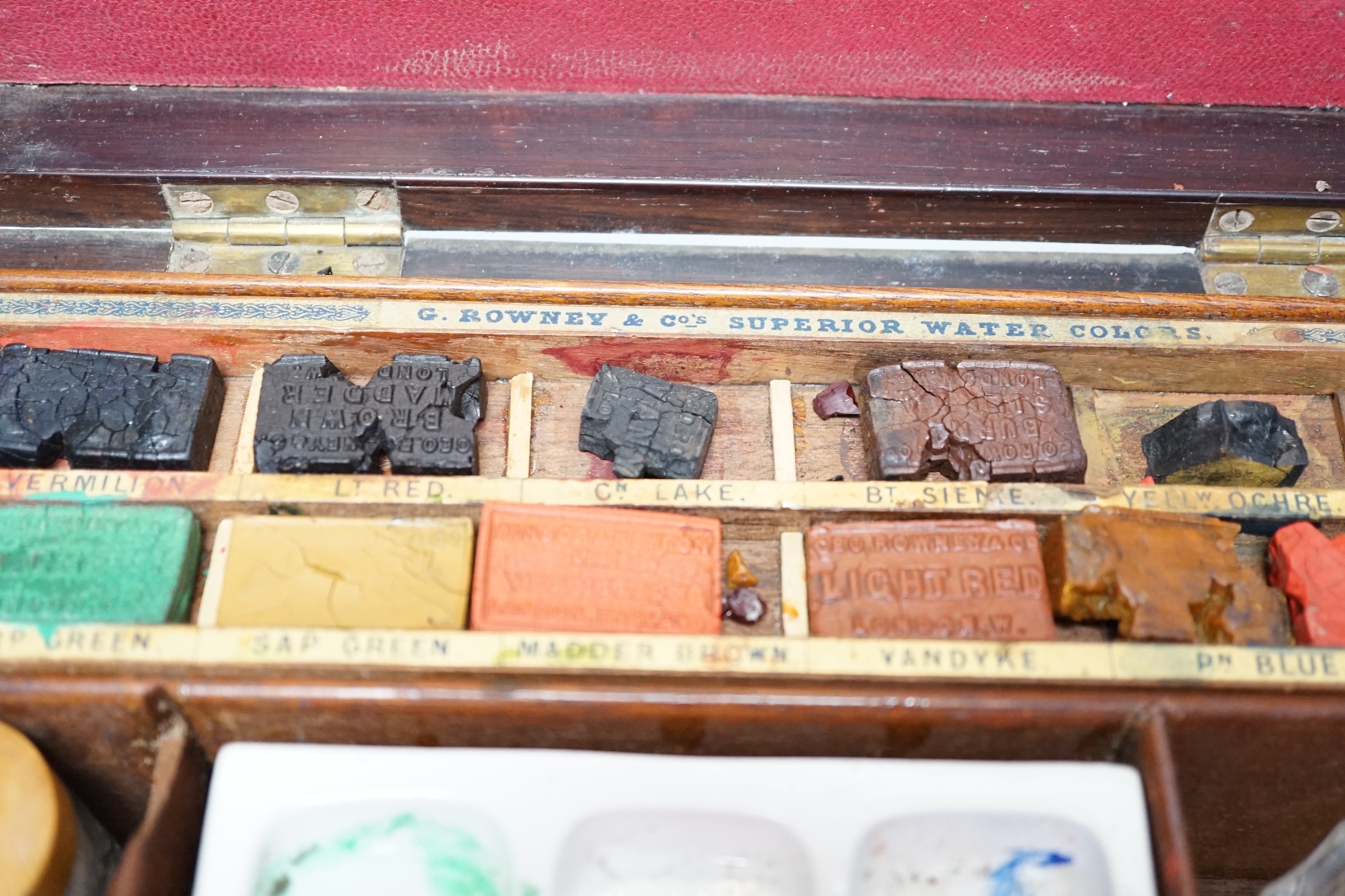An Edwardian G Rowney & Co brass mounted artist’s paint box with watercolour blocks, tubes and charcoal sticks